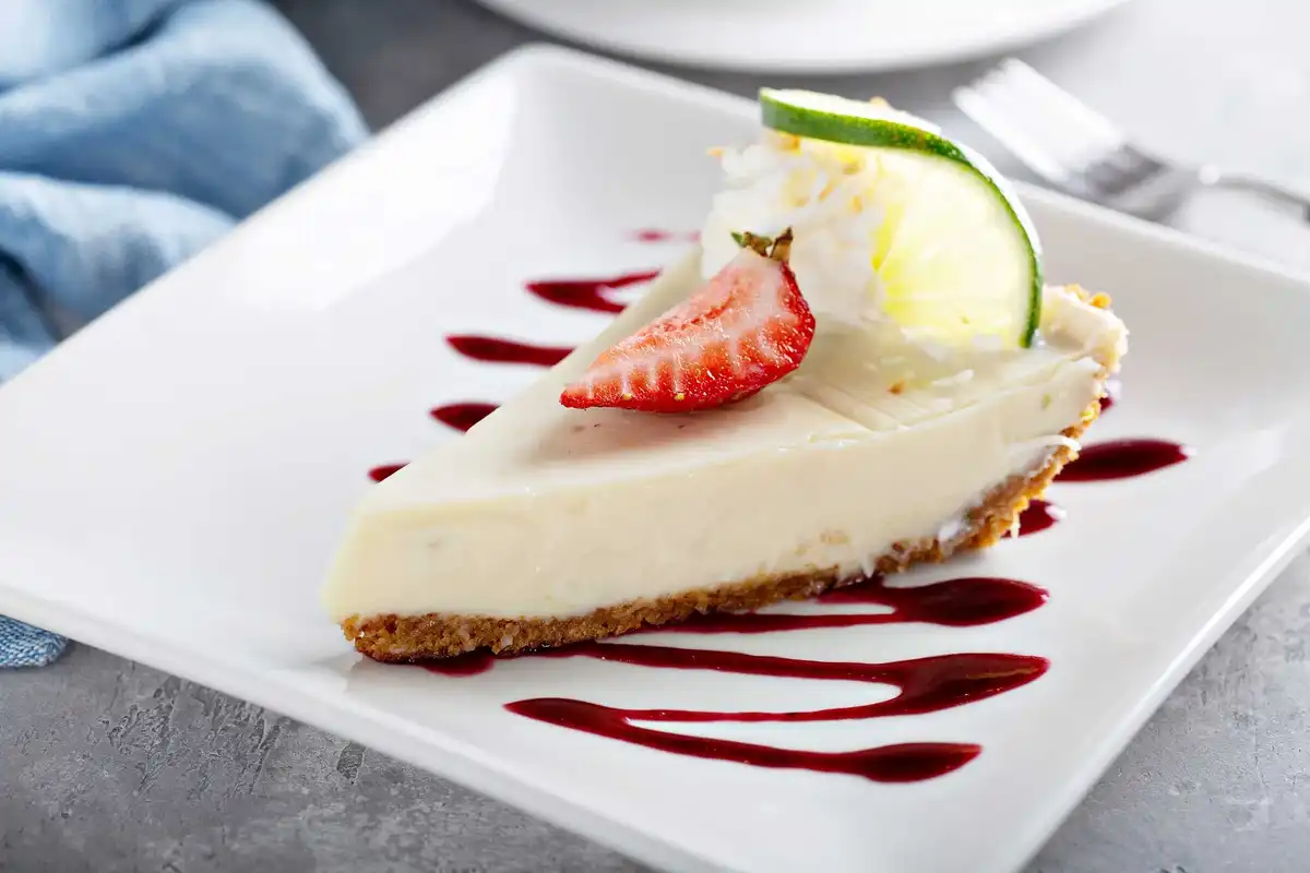 Key lime pie slice with strawberry and lime garnish